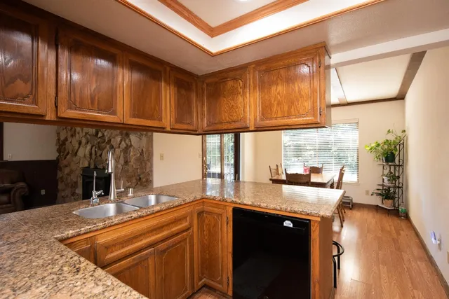 a kitchen with granite countertop wooden cabinets a sink and dishwasher with wooden floor