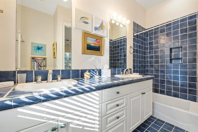 a bathroom with a granite countertop double vanity sink a mirror and a bathtub