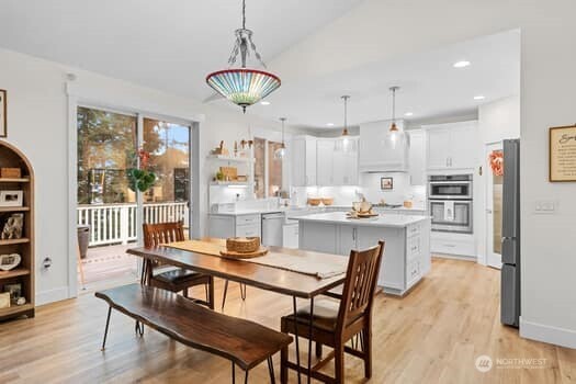 10218 45th Street East Edgewood, WA 98372 - Photo 7 of 34 a dining room with stainless steel appliances kitchen island granite countertop a dining table chairs and a refrigerator