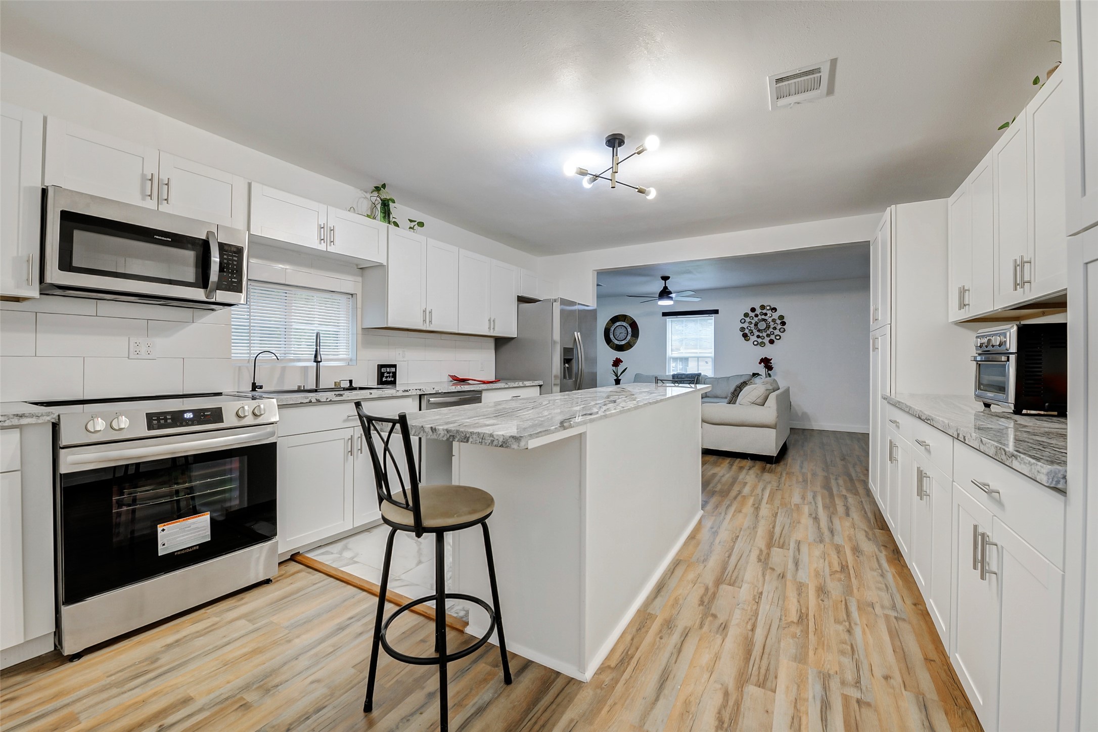 706 Beaumont Street Anahuac, TX 77514 - Photo 1 of 39 a kitchen with granite countertop a stove top oven a sink dishwasher a dining table and chairs with wooden floor