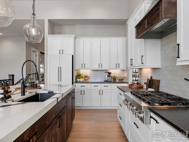 a kitchen with stainless steel appliances a stove center island a dining table and chairs with wooden floor