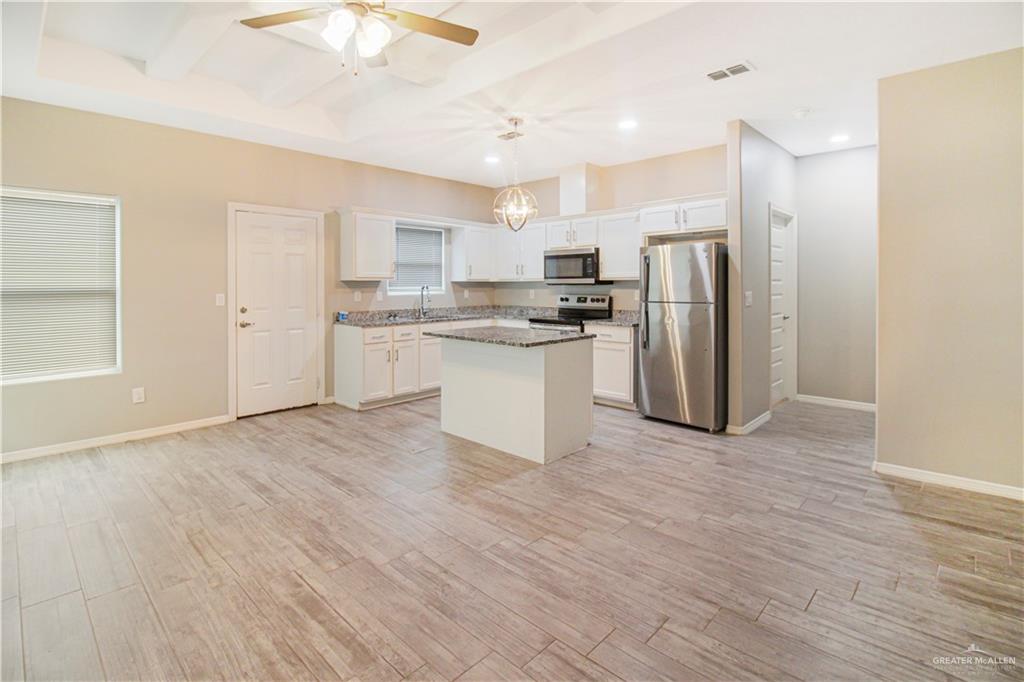1809 Stauffer Street, Unit 4 Weslaco, TX 78596 - Photo 4 of 13 Kitchen featuring stainless steel appliances, white cabinetry, a center island, a ceiling fan, and hanging light fixtures