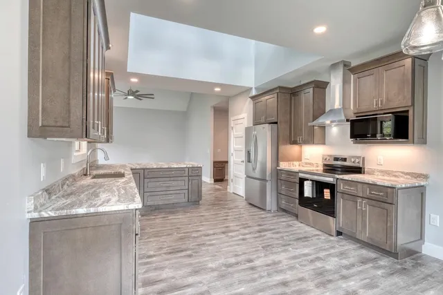 a kitchen with kitchen island granite countertop a stove top oven a sink dishwasher a dining table and chairs with wooden floor