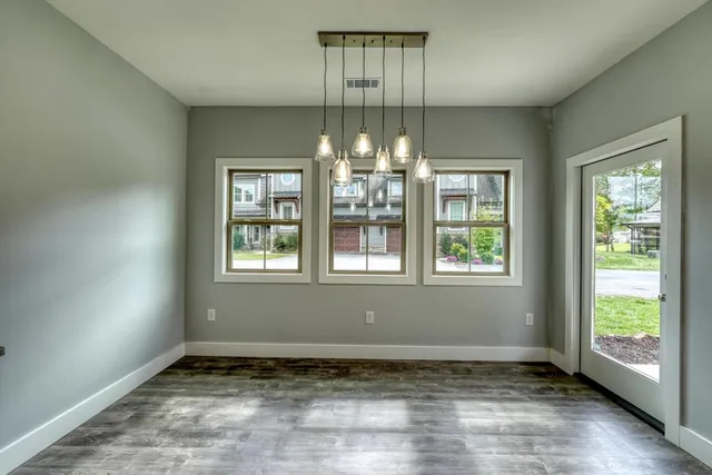 a view of an empty room with window and chandelier fan
