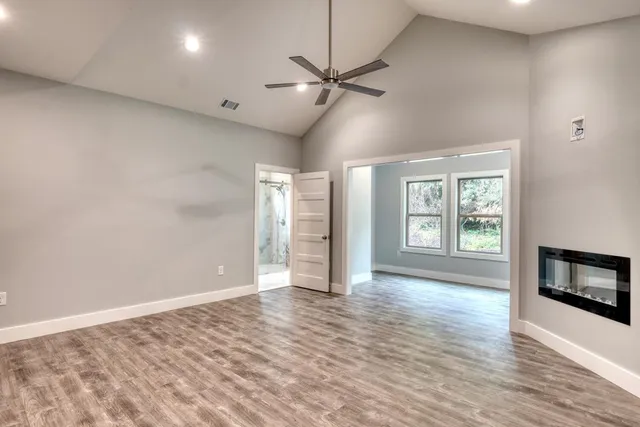 a view of an empty room with a window and wooden floor