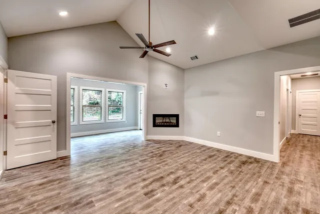 a view of an empty room with a window and wooden floor