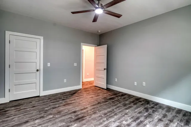 a view of an empty room with window and wooden floor