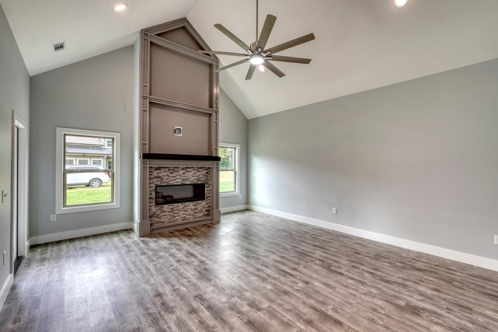 98 Brett Way Hiawassee, GA 30546 - Photo 8 of 39 an empty room with windows a fireplace and a ceiling fan