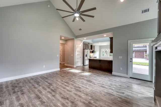 a view of an empty room with a kitchen and a window