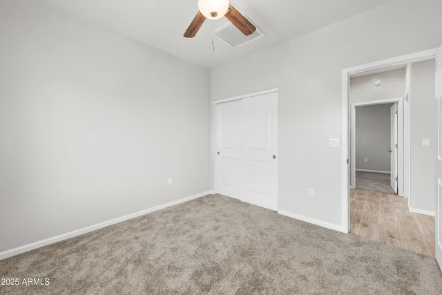 an empty room with a ceiling fan and carpet