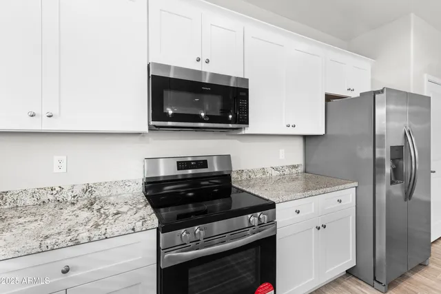 a kitchen with stainless steel appliances granite countertop white cabinets and a stove a oven with white countertops