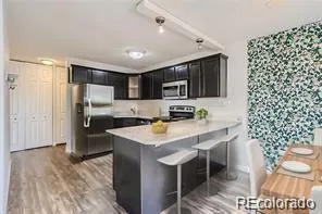 a kitchen with stainless steel appliances a sink a stove a refrigerator cabinets and a dining table