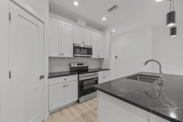a kitchen with stainless steel appliances granite countertop a sink a stove and a refrigerator