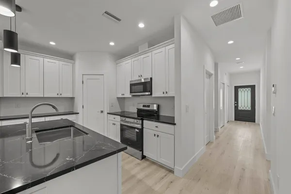 a kitchen with granite countertop a sink a stove and refrigerator