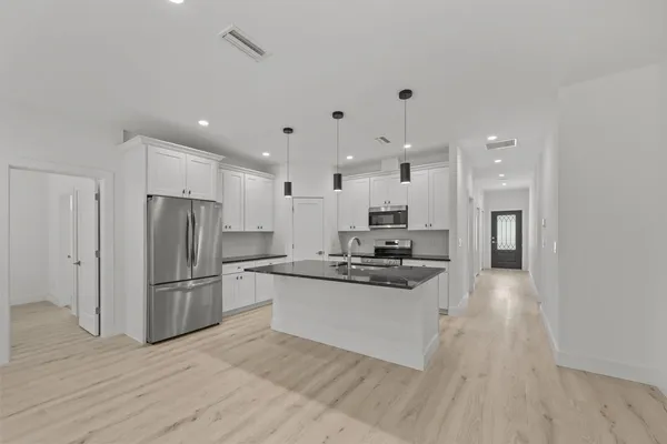 a kitchen with stainless steel appliances granite countertop a refrigerator stove top oven and sink