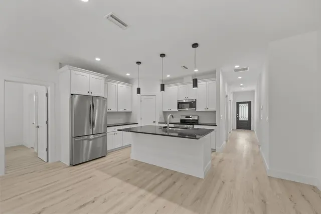 a kitchen with stainless steel appliances granite countertop a refrigerator stove top oven and sink