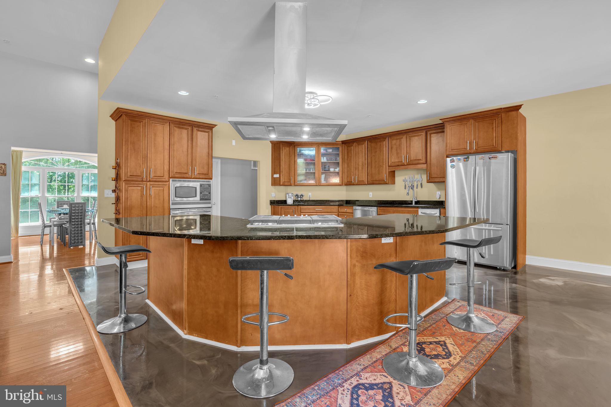 13716 Molly Berry Road Brandywine, MD 20613 - Photo 9 of 75 a kitchen with stainless steel appliances granite countertop a refrigerator a stove a sink a dining table and chairs with wooden floor