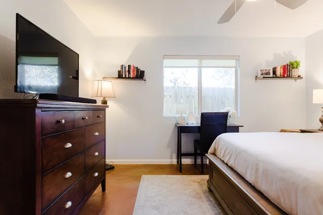 a bedroom with a bed and a flat tv screen on dresser