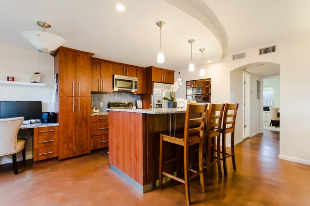 a kitchen with stainless steel appliances kitchen island granite countertop a table chairs and a refrigerator