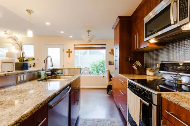 a kitchen with stainless steel appliances granite countertop sink stove top oven and cabinets