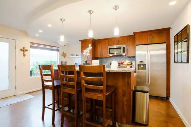 a kitchen with stainless steel appliances a refrigerator a stove a microwave oven a dining table and chairs with wooden floor