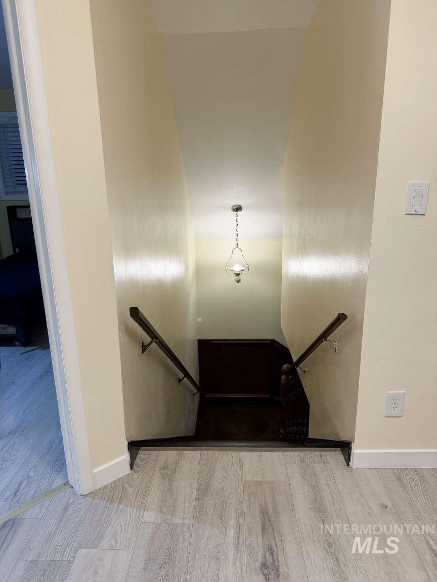 1158 South Powerline Road Nampa, ID 83686 - Photo 38 of 46 Stairwell with light wood-finish flooring, dark wood handrails, and a hanging pendant light fixture