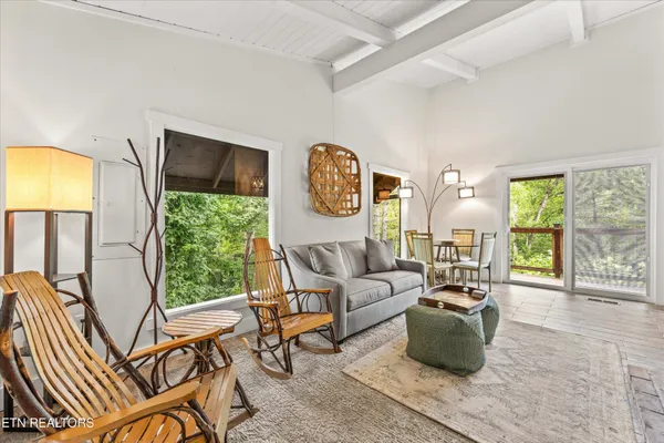 a living room with furniture a floor to ceiling window and a flat screen tv