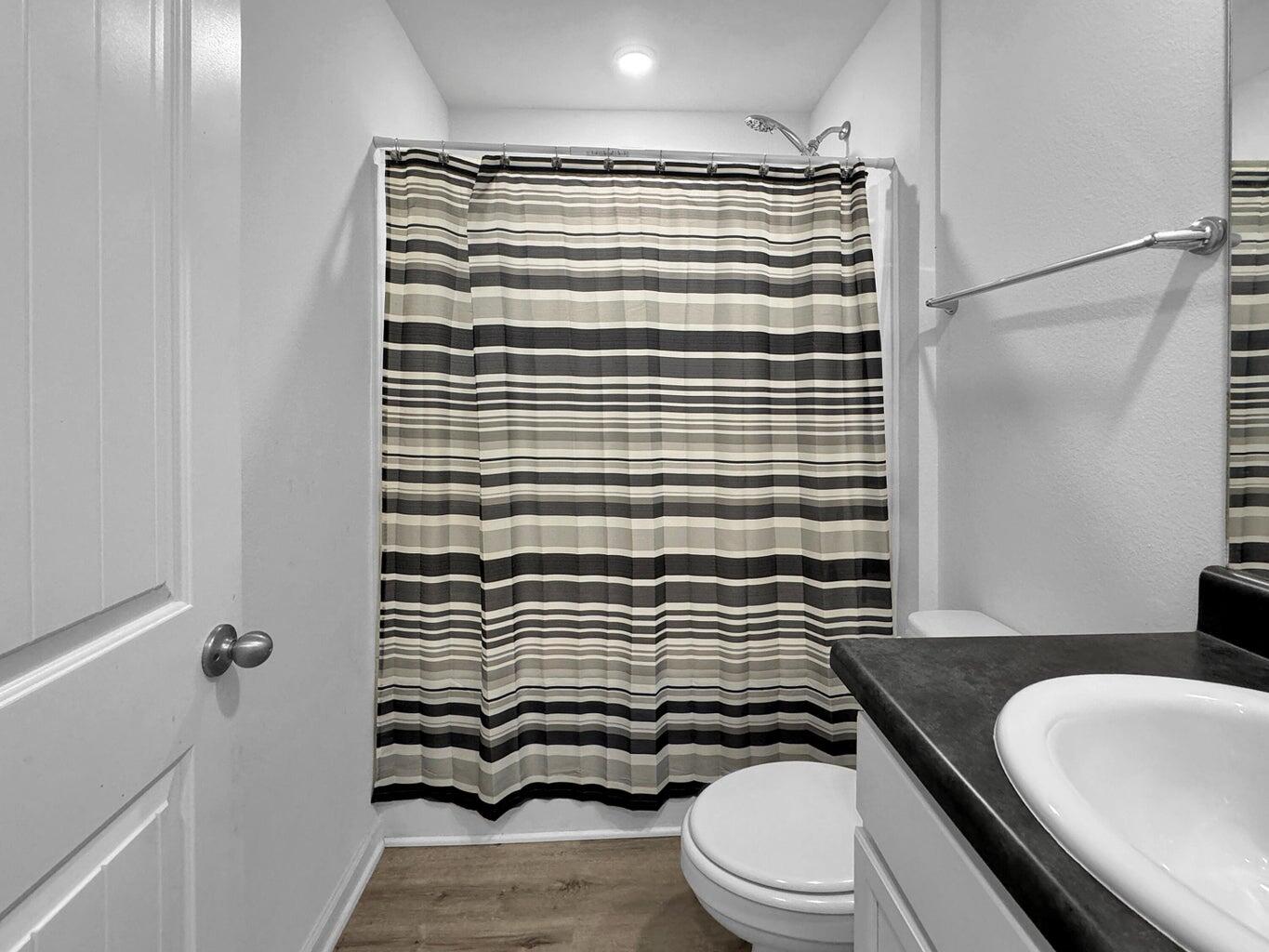 4695 Perception Circle Milton, FL 32570 - Photo 21 of 30 a bathroom with a sink a toilet a mirror and shower curtain