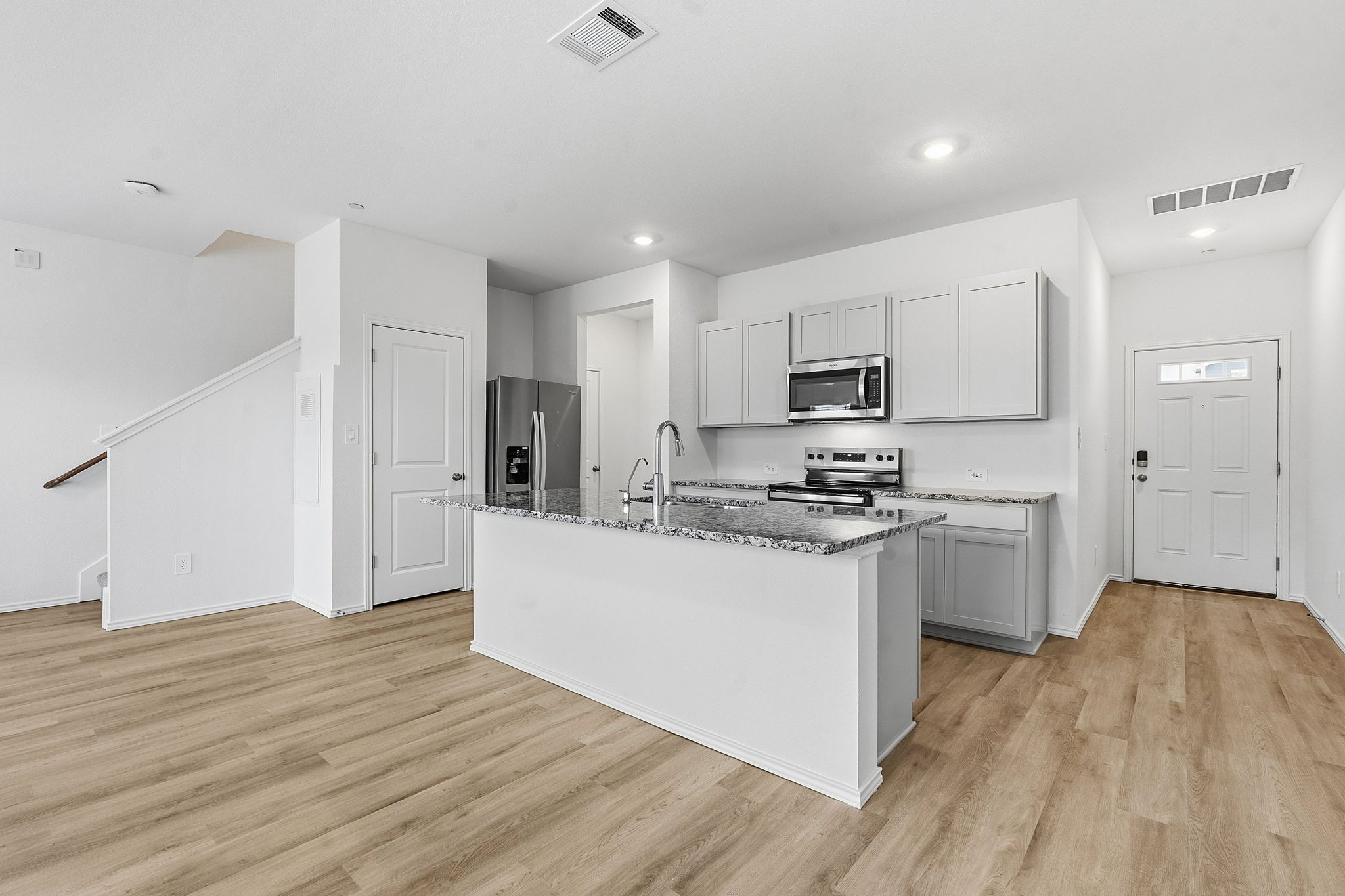 164 Cinnabar Lane, Unit 3 Kyle, TX 78640 - Photo 5 of 20 Open-concept kitchen featuring an island with a breakfast bar, stainless steel appliances, granite countertops, and light gray cabinetry