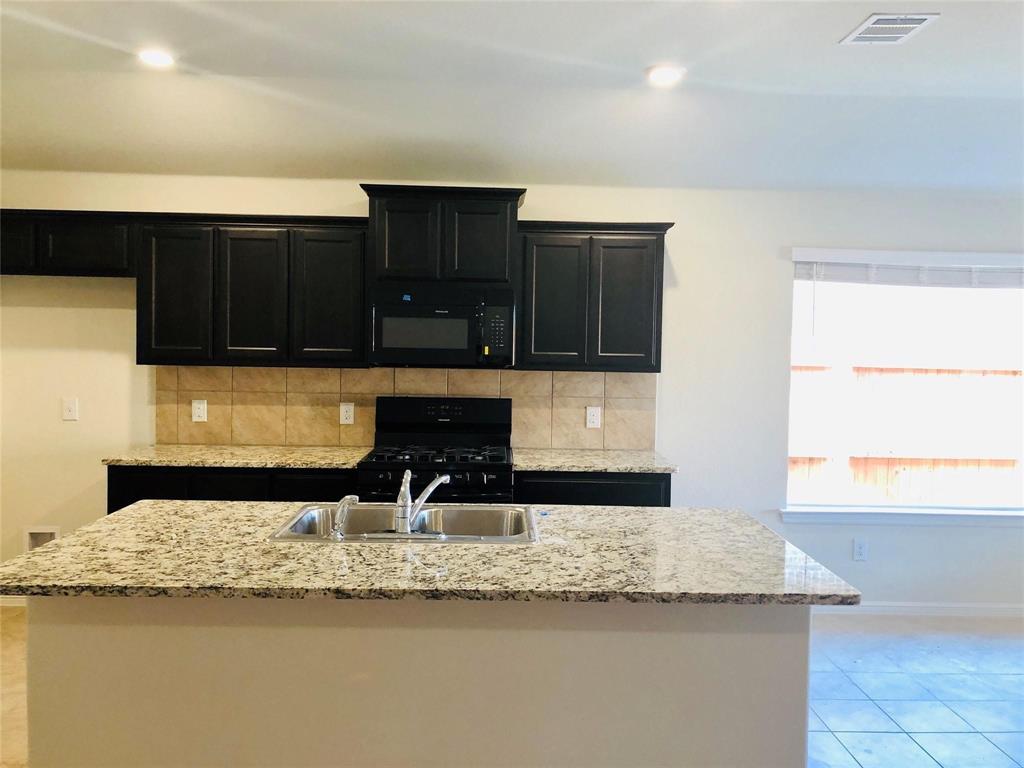 925 Rutherford Drive Crowley, TX 76036 - Photo 5 of 17 a kitchen with granite countertop a sink and a stove top oven