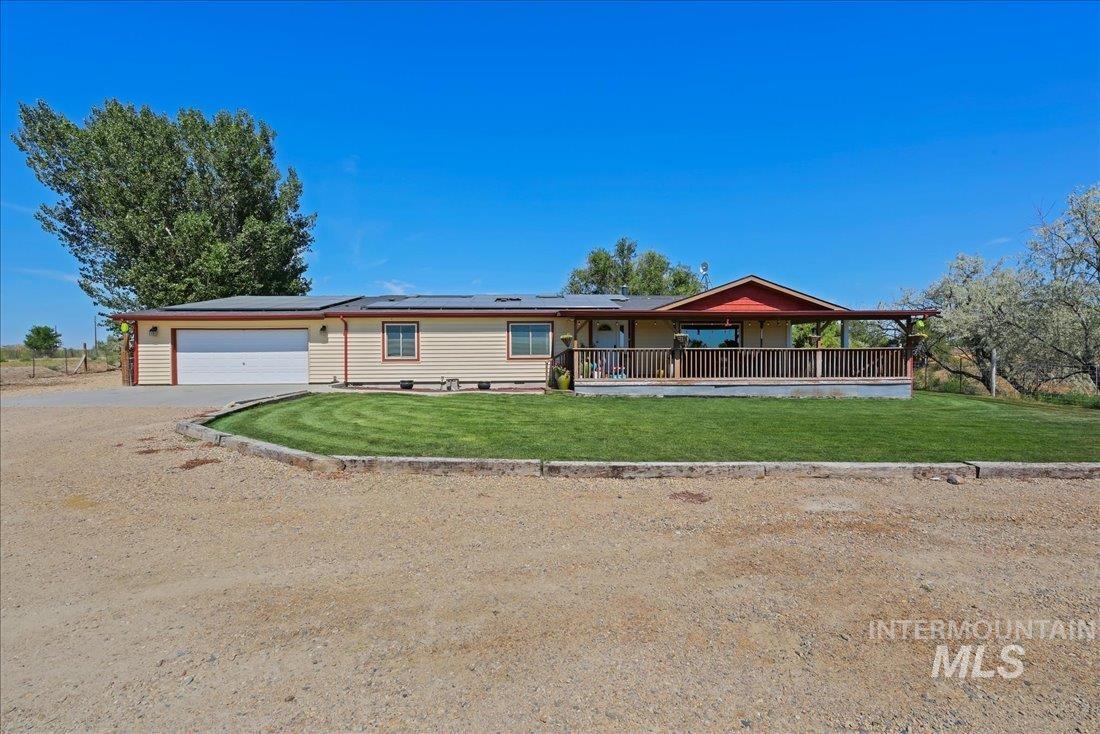 25590 Jacks Road Parma, ID 83660 - Photo 1 of 1 View of front of home with solar panels, driveway, a garage, a front yard, and a porch