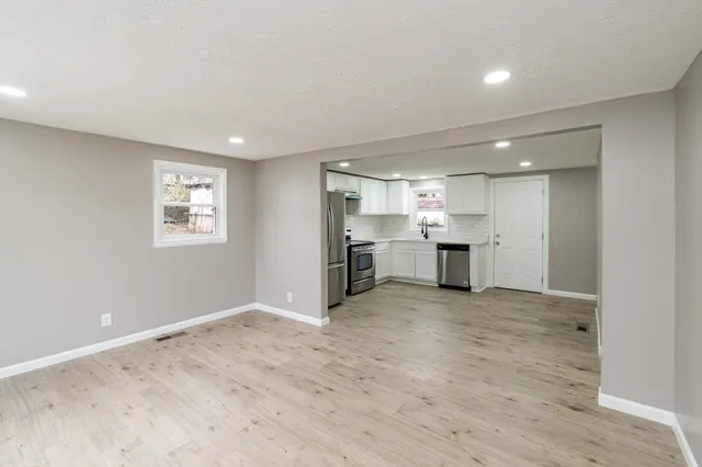 a view of a kitchen with a sink and dishwasher a refrigerator with wooden floor