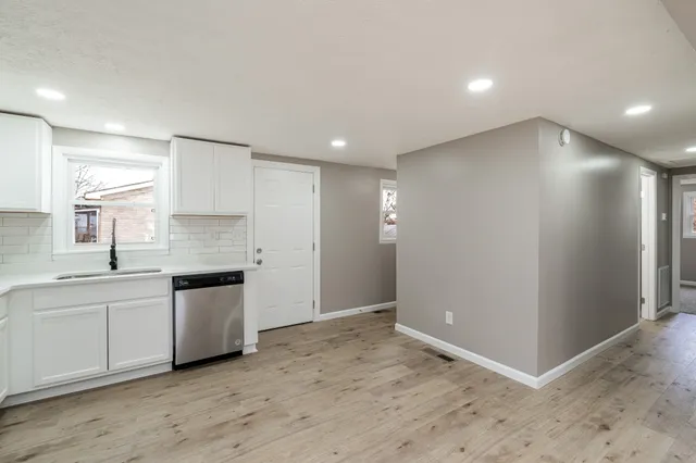 a view of a kitchen with a sink and dishwasher a stove top oven with wooden floor