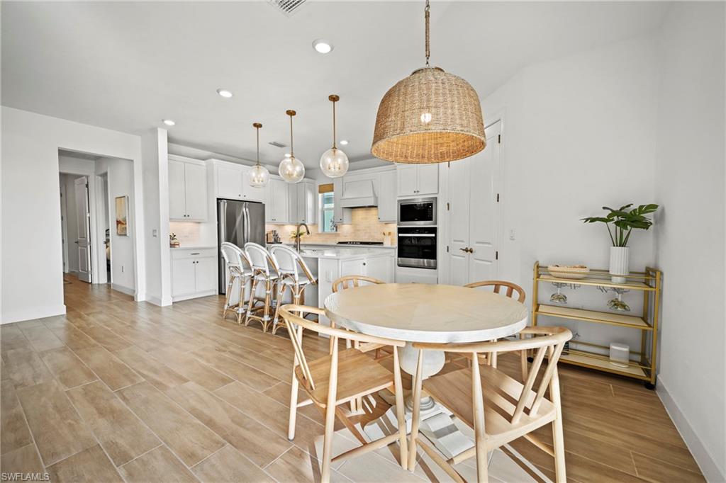 15764 Appalachian Drive Babcock Ranch, FL 33982 - Photo 11 of 46 a kitchen with stainless steel appliances kitchen island granite countertop a table chairs and a white cabinets