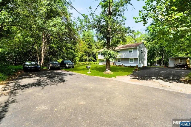 a view of a house with a yard and large trees