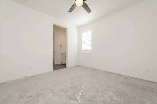 an empty room with a window and a ceiling fan