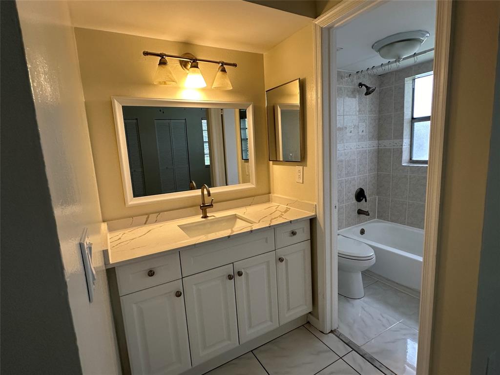 9971 Twin Lakes Drive, Unit 9G Coral Springs, FL 33071 - Photo 10 of 13 a bathroom with a double vanity sink toilet mirror and bathtub