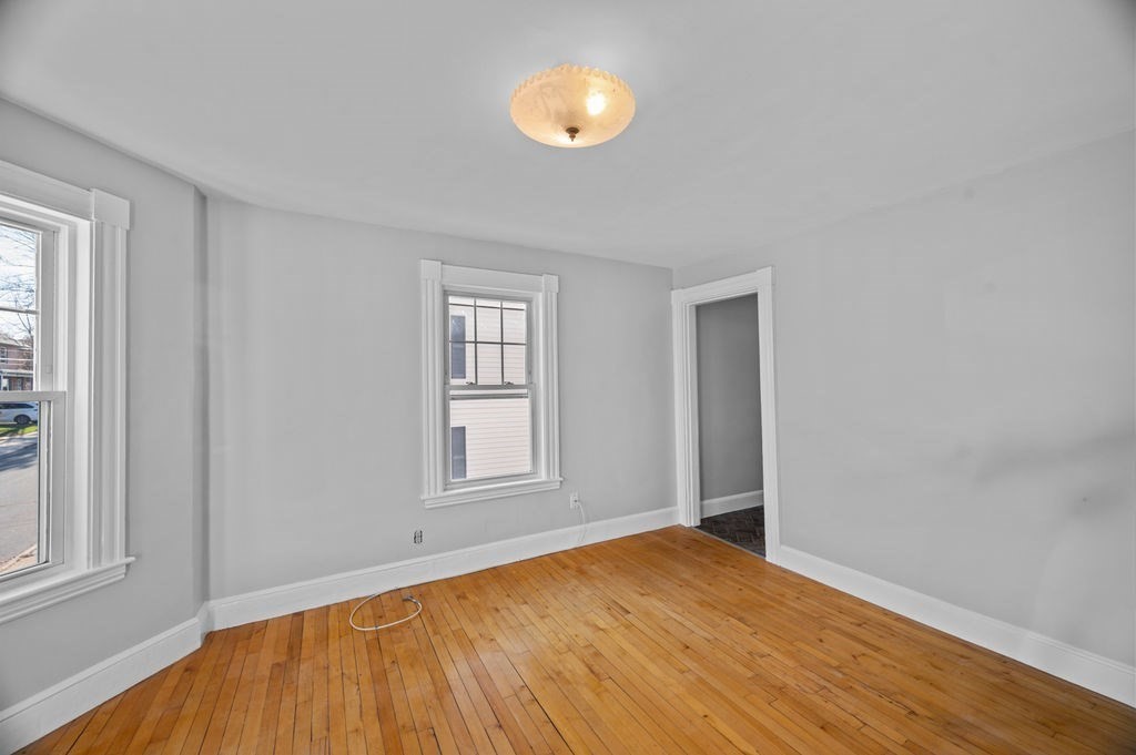 13 Giles Avenue, Unit 2 Beverly, MA 01915 - Photo 4 of 27 an empty room with wooden floor and windows