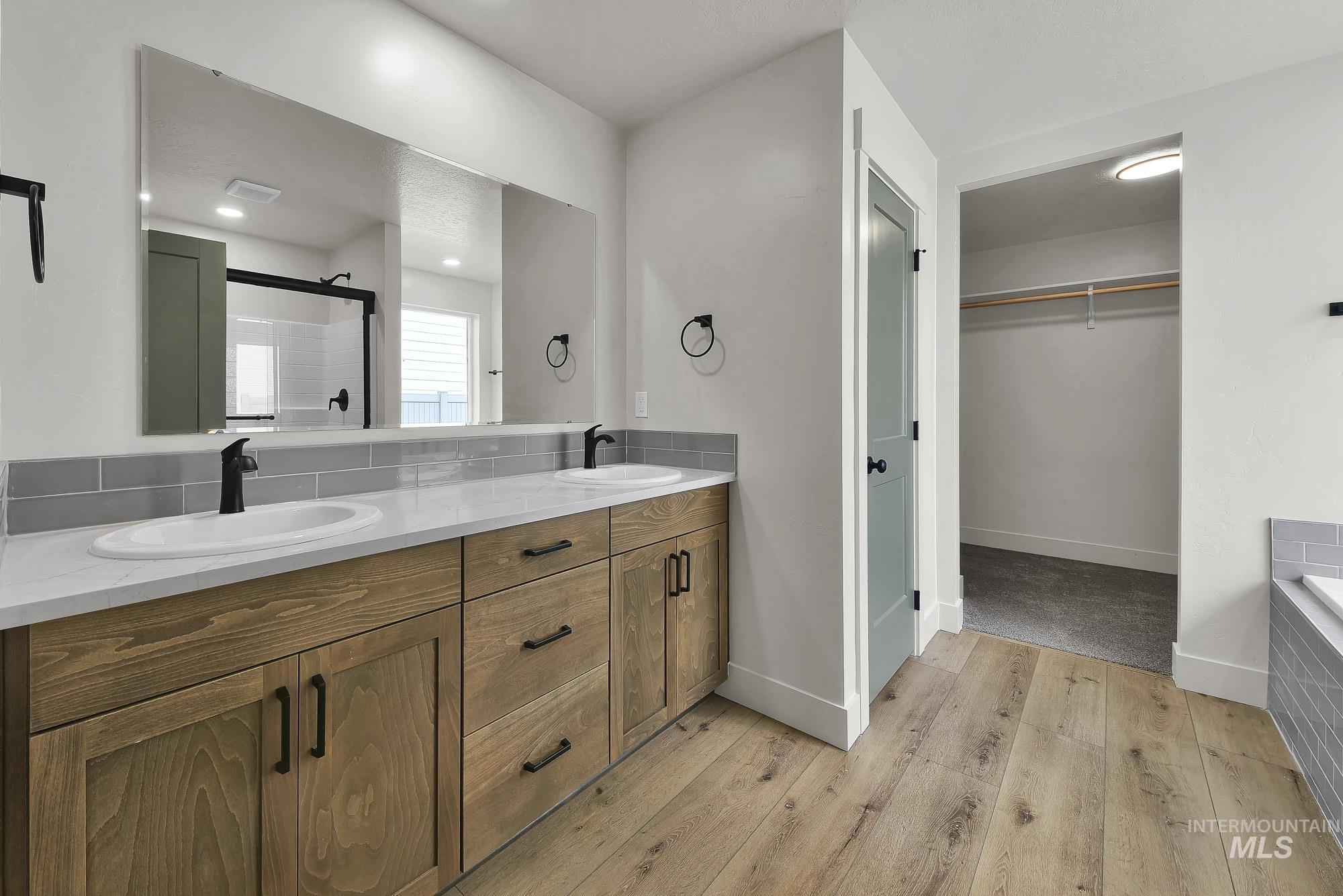 1130 Velvet Loop Wilder, ID 83676 - Photo 20 of 35 Bathroom vanity featuring dual under-mount sinks with matte black faucets, a large frameless mirror, and a wood-finish cabinet with black hardware