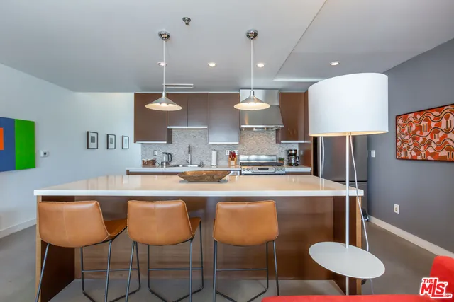 a kitchen with stainless steel appliances granite countertop a sink a stove a refrigerator a microwave oven with white cabinets and wooden floor