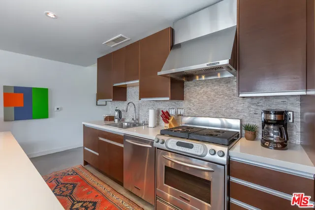 a kitchen with stainless steel appliances a sink dishwasher a stove a microwave oven and a refrigerator with wooden floor