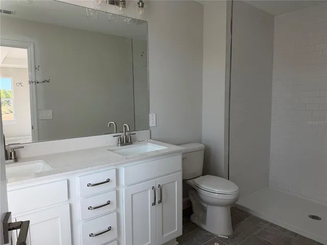 a bathroom with a granite countertop toilet sink and mirror