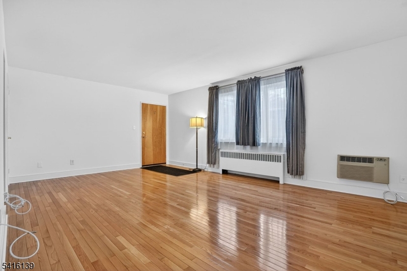 10 Troy Drive, Unit 10A Springfield, NJ 07081 - Photo 5 of 23 a view of an empty room with wooden floor and a window