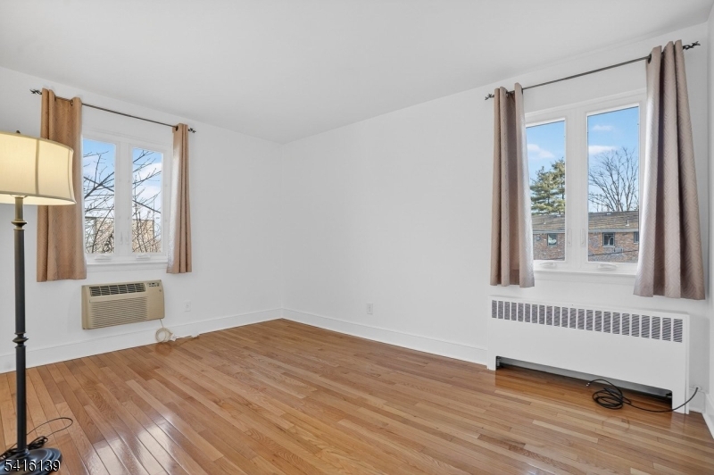 10 Troy Drive, Unit 10A Springfield, NJ 07081 - Photo 8 of 23 a view of an empty room with a window and wooden floor