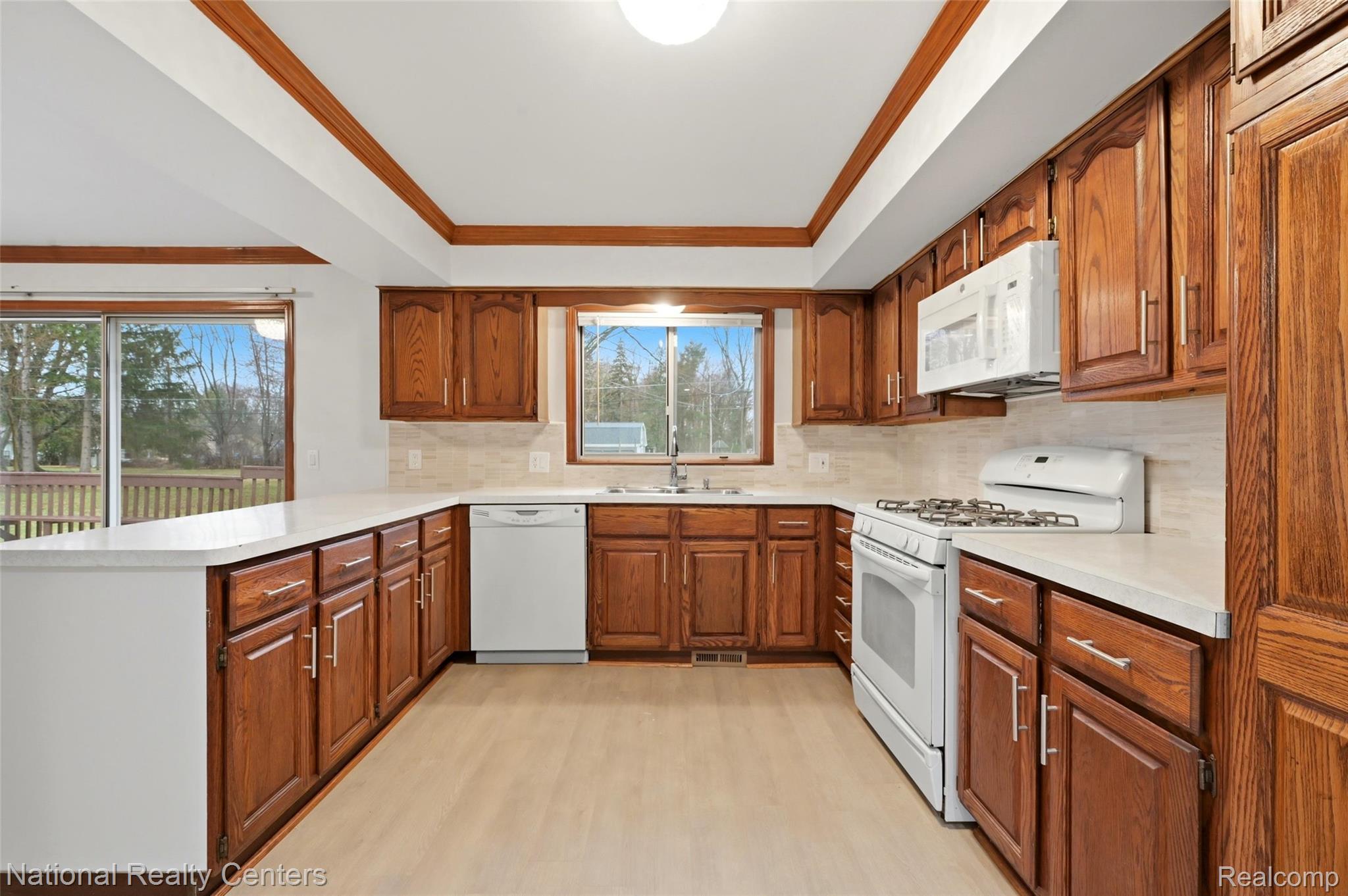 37625 Ryan Road Sterling Heights, MI 48310 - Photo 14 of 30 Kitchen featuring wood finish cabinets, white appliances, light countertops, light wood finished floors, and a tray ceiling