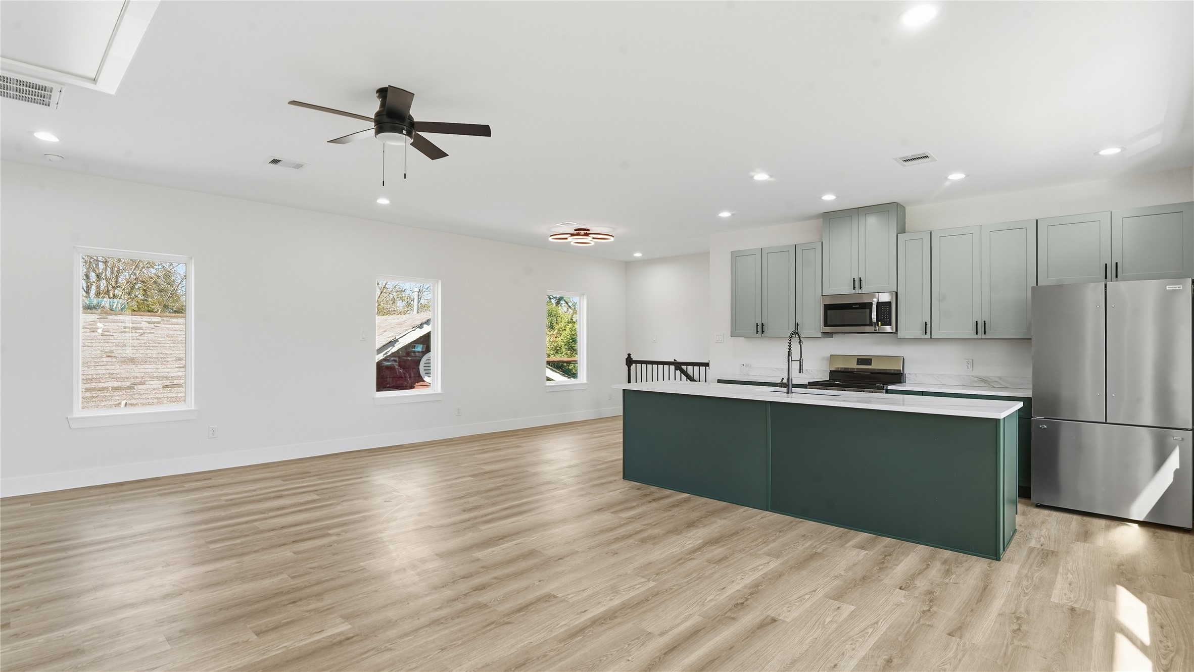 a kitchen with stainless steel appliances kitchen island granite countertop a refrigerator a stove and a wooden floors
