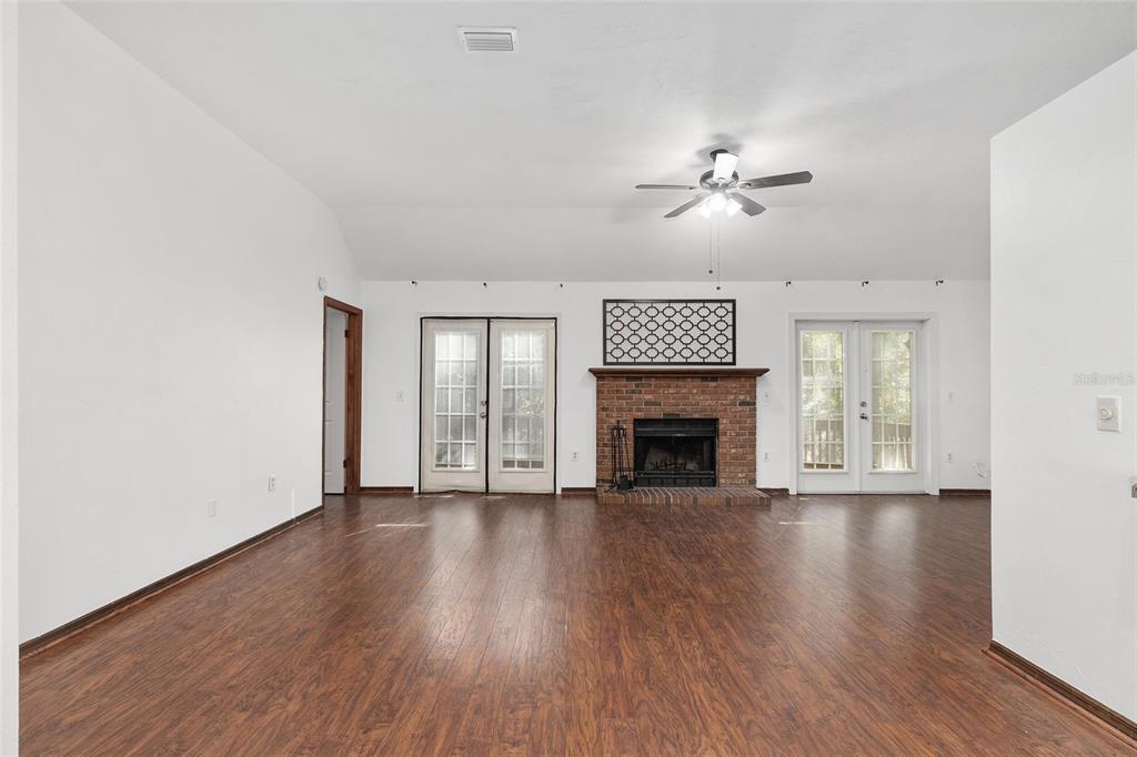 8305 Southwest 46 Lane Gainesville, FL 32608 - Photo 11 of 65 a view of an empty room with wooden floor fireplace and a window