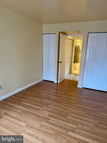 a view of an empty room with wooden floor and cabinet