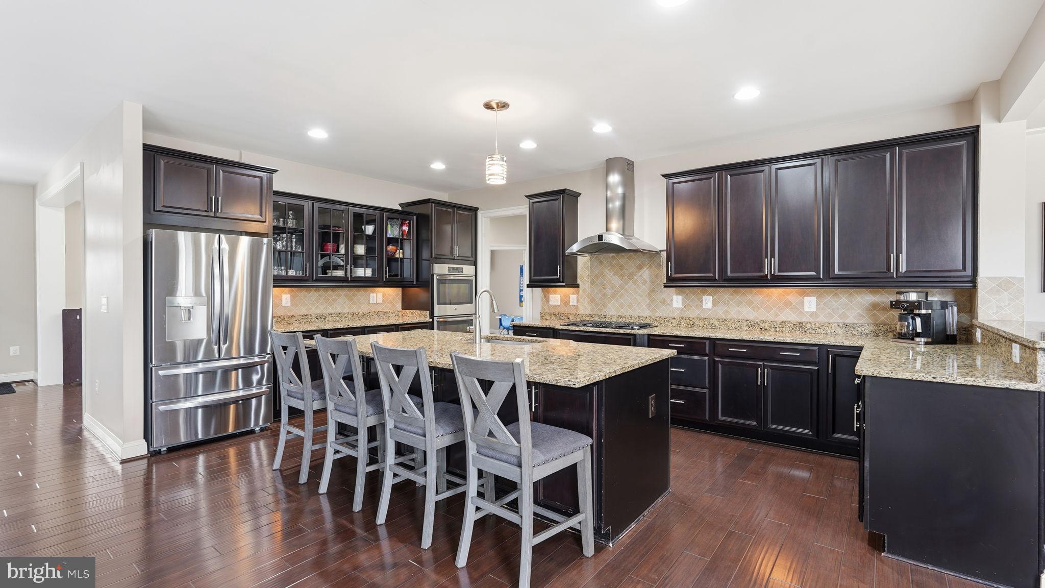 111 Pear Blossom Road Stafford, VA 22554 - Photo 9 of 68 a kitchen with stainless steel appliances kitchen island granite countertop wooden floors and wooden cabinets