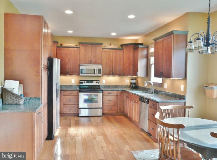 7224 Gilardi Road Boonsboro, MD 21713 - Photo 18 of 30 a kitchen with kitchen island granite countertop wooden cabinets and a refrigerator